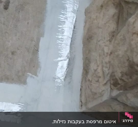 איטום פינה עם חומר לבן ומבריק על קיר אבן